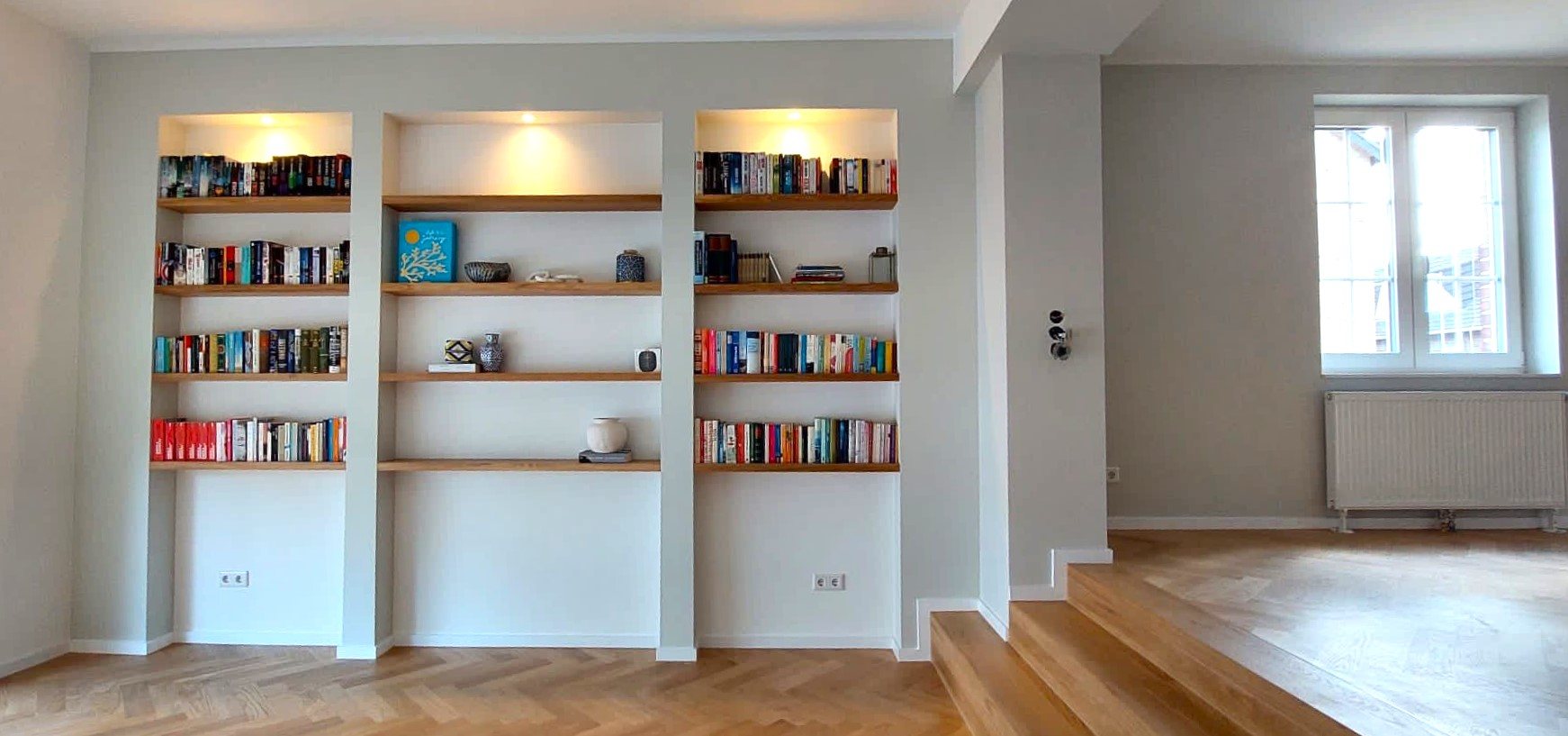 Fertiggestellter Wohnbereich mit integrierten Bücherregalen und Parkett